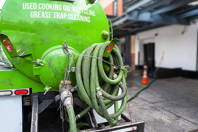 a technician pumping a grease trap in a commercial building in Dedham